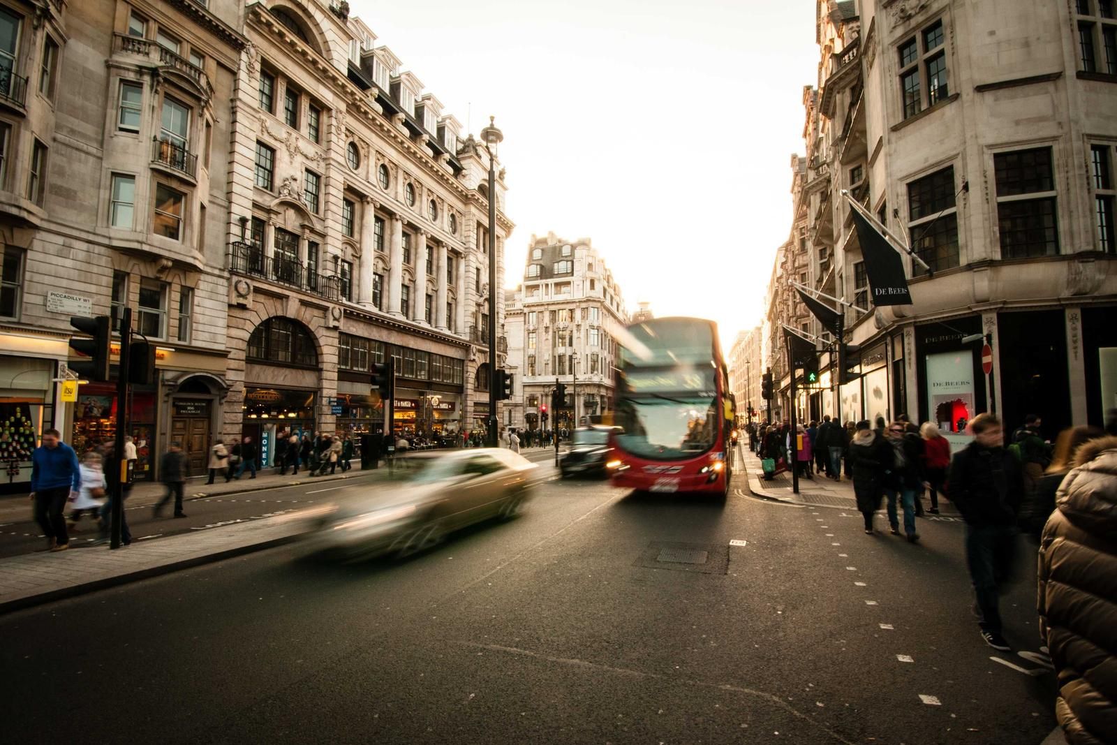 Busy London street scene with red double-decker bus and pedestrians among historic Georgian architecture and storefronts